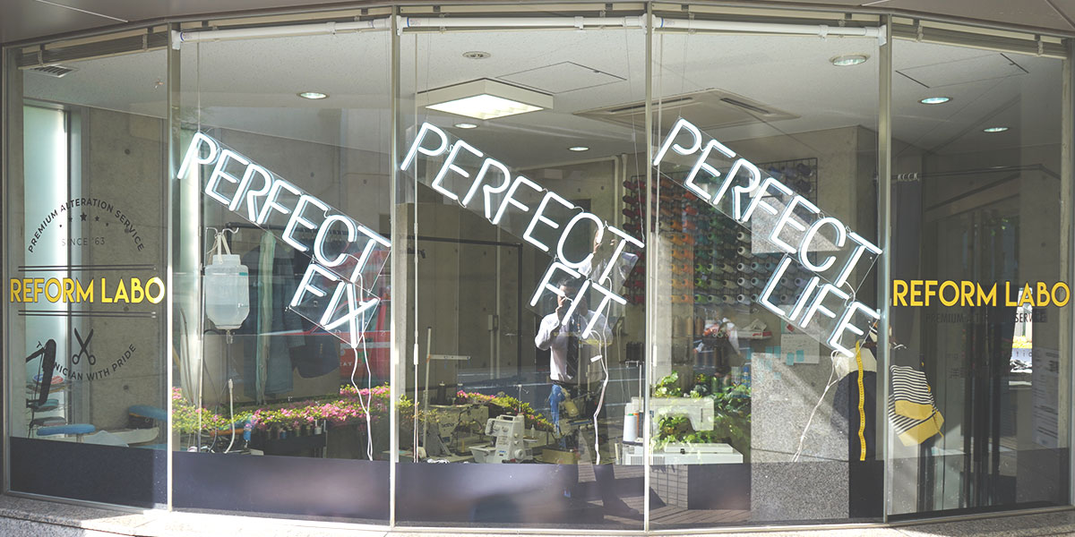 リフォームラボ大井町店の外観。ガラス張りの店内にPERFECT FIX・PERFECT FIT・PERFECT LIFEのネオンサイン